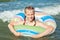 Happy child playing in blue water of ocean on a tropical resort at the sea.  Cheerful little girl swims in the blue ocean with an