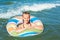 Happy child playing in blue water of ocean on a tropical resort at the sea.  Cheerful little girl swims in the blue ocean with an