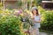 Happy child playing little gardener and watering hydrangea bush in sunny summer garden