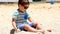 Happy child playing with sand at the beach in summer. Kids playing in the sands. This activity is good for sensory