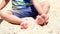 Happy child playing with sand at the beach in summer. Kids playing in the sands. This activity is good for sensory