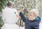 Happy child playing with a snowman outdoor in winter. Cute little child building a snowman and having fun in park or backyard