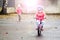 Happy child riding a bicycle in the fall. Cute little girl in safety helmet riding a bike outdoors. Little girl on a red bicycle.