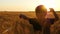 A happy child runs through a field of ripe, golden wheat at sunset.