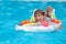 A happy child safely swims in the pool on an air mattress and in armbands