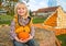 Happy child sitting on haystack with pumpkin