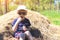 Happy child in sunglasses. Family weekend on a farm. Funny boy is eating fresh cherry and sitting on a stack of hay. Summer