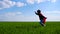 A happy child in a superhero costume in a red cloak runs across a green field