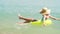 Happy child swimming in blue water at the sea. Summer vacations. Girl on inflatable ring ride on breaking wave. Kid