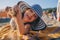 Happy child in swimsuit relaxing on the summer beach, lying on towel and playing with sand. Warm weather, cozy mood. Traveling on