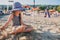 Happy child in swimsuit relaxing on the summer beach and playing with sand. Warm weather, cozy mood.