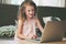 Happy child using laptop at home. School girl learning with computer and internet