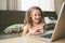 Happy child using laptop at home. School girl learning with computer and internet