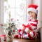 Happy child wearing Christmas pajamas sitting on windowsill