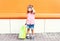 Happy child wearing a sunglasses with shopping bags in city over colorful background
