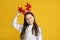 Happy childhood and Christmas. Cheerful girl with horns in sweater