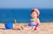 Happy childhood, happy family vacation. Cute child on the sea background. Happy little girl playing with sand on the beach of sea