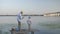 Happy childhood, loving dad spends time with his dear son fishing on pier by river during summer vacations in