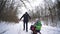 Happy childhood at winter time, father walking with kids on sled in snowy forest