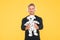 Happy childish middle-aged man listen to music in headphones holding dalmatian toy dog yellow background, playing