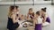 Happy children ballet students and their teacher are eating pizza during lunch break between dancing lessons. Girls are