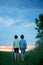 Happy children, boy brothers, holding pair of sneakers in hands, walking on a rural path