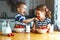 Happy children brother and sister eating strawberries with milk