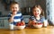 Happy children brother and sister eating strawberries with milk