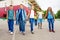 Happy children carry rucksacks, walk near school