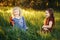 Happy children girls playing dolls in park. Cute adorable kids sitting in grass on meadow playing toys. Happy childhood authentic