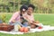 Happy children have a picnic in summer park, cute curly hair African girl with Asian buddy friend studying, reading book together