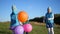 Happy children jumping, laughing and smiling with balloons. Fun outdoors