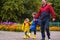 Happy children laugh, rush and run to school, dressed in raincoats, with a briefcase behind a backpack