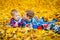 Happy children lie on autumn leaves on a blanket with red apples in their hands. Funny children outdoors in the autumn Park.