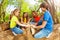 Happy children playing with logs in the forest