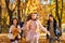 happy children playing together and scattering yellow leaves, portrait of big family in autumn city park, children running with