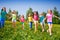 Happy children run and hold hands in green field