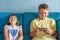 Happy children are sitting together on the couch, smiling and watching funny videos using the phone