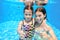 Happy children swim in pool underwater, girls swimming