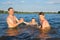 Happy children with their father play in the water on a sunny day at sunset. Family games on vacation. Active lifestyle