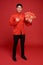 Happy Chinese new year. Asian man holding angpao or red packet monetary gift isolated on red background. text means great luck