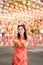 Happy Chinese new year. A young lady wearing traditional cheongsam qipao dress holding ancient gold money and orange fresh in