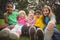 Happy classmates sitting in grass and having arms around