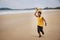 Happy colored boy and African American boy playing yellow toy airplane and running by wearing yellow sweater. Having fun on beach