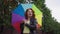 Happy confident beautiful retro woman spinning colorful umbrella standing on town street outdoors looking at camera