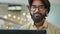 Happy confident Indian Arabian ethnic multiracial bearded businessman in glasses looking at camera in office, positive