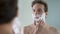 Happy and confident male putting shaving cream on his face before shaving