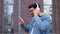 Happy cool indian man wearing headphones and glasses dancing alone on street.