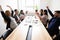 Happy corporate staff celebrating shared success seated at boardroom desk