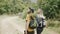 A happy couple backpackers walking by forest's path and holding hands